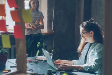 Two women work in a bright office setting.